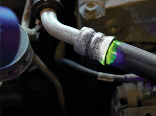 Technician performing A/C leak detection under the hood